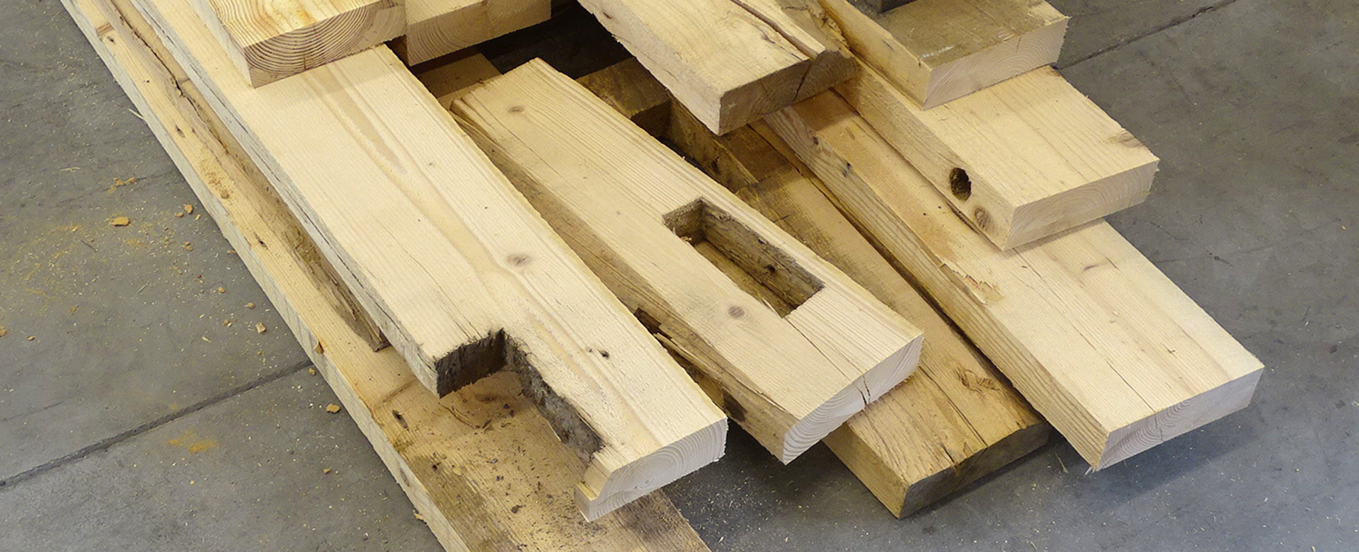 Stacked waste wood planks on the floor of a hall.